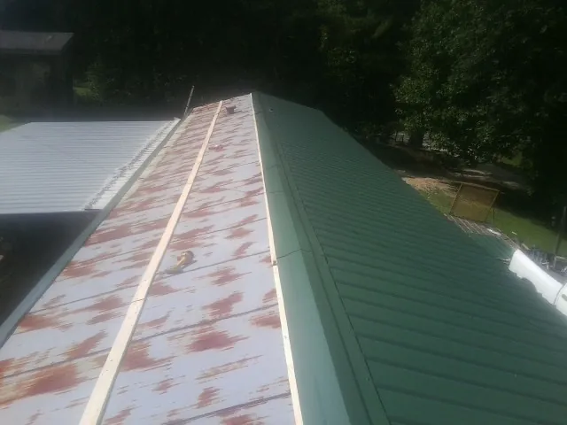 Old rusted panels beside newly installed green metal roofing — Wind Damage Roof Repair by Roofing Brothers in Medicine Lodge