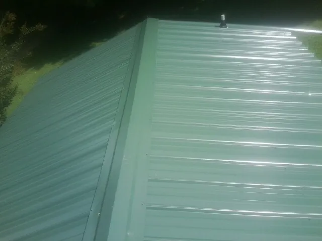 New green metal panels meeting at the ridge of a roof — Flat Roof Repair work by our crew in Medicine Lodge