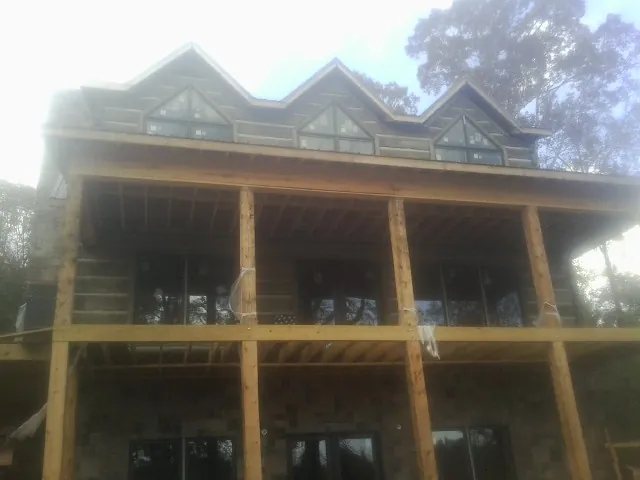 Dormers and porch framing on a large log home under construction — Roof Coating work by our crew in Medicine Lodge