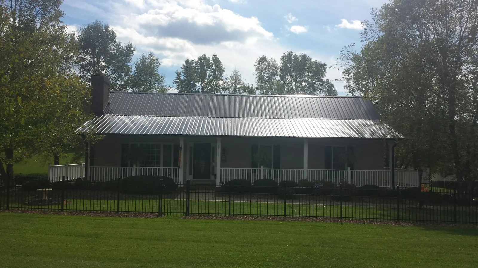 Gray metal roof on a brick ranch with a full width front porch — Gutter Guard Installation work by our crew in Medicine Lodge