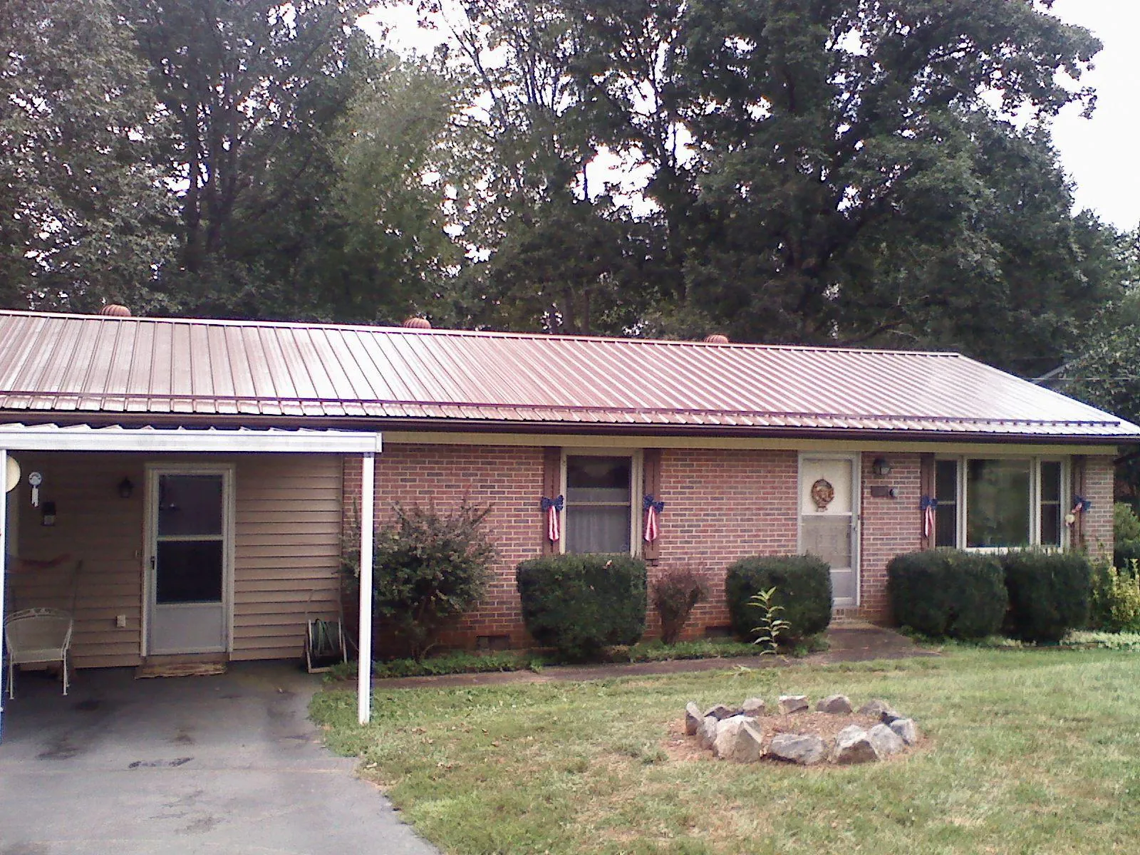 Bronze metal roof and carport on a brick ranch home — Roof Repair work by our crew in Medicine Lodge