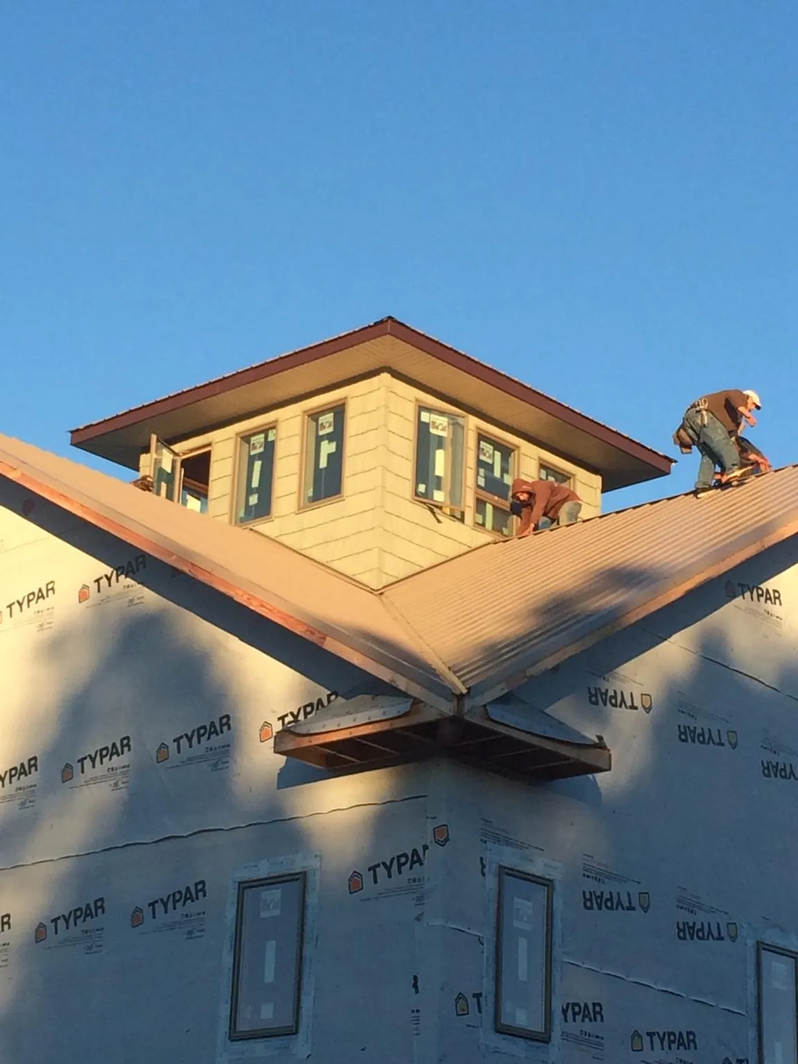 Roofers working around a rooftop cupola on a new metal roof at sunset — Roof Waterproofing in Medicine Lodge by Roofing Brothers